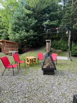 a group of chairs and a wood stove in a yard at Chalet Le Mona in Notre-Dame-Des-Bois