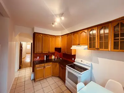 a kitchen with wooden cabinets and a stove top oven at Urban Comfort 3BR Apartment in NDG in Montréal