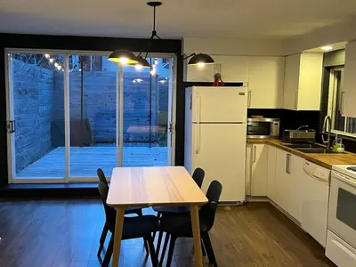 a kitchen with a table and a white refrigerator at Appartement Mid Century 2 Chambres avec Jardin in Montréal