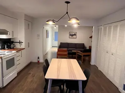 a kitchen and living room with a table and a couch at Appartement Mid Century 2 Chambres avec Jardin in Montréal