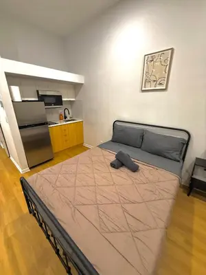 a large bed in a room with a kitchen at Big studio 4 persons apartment with Private FREE Parking in Montréal