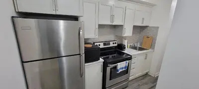 a kitchen with white cabinets and a stainless steel refrigerator at Comfortable condo in Montreal in Montréal