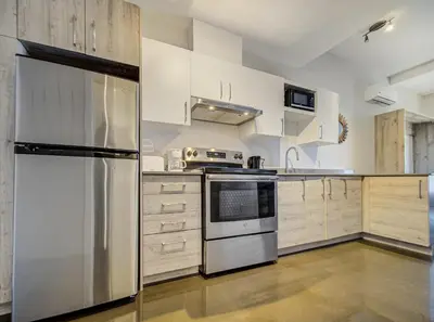 a kitchen with white cabinets and a stainless steel refrigerator at Appartement au centre de Montréal in Montréal