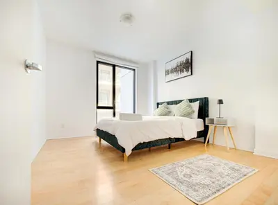 a white bedroom with a bed and a rug at Charmant appartement au vieux port de Montréal in Montréal