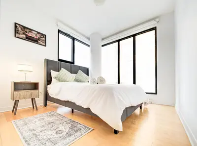 a bedroom with a large bed and large windows at Charmant appartement au vieux port de Montréal in Montréal