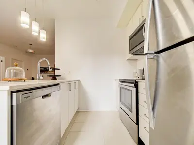 a kitchen with white cabinets and a stainless steel refrigerator at Charmant appartement au vieux port de Montréal in Montréal