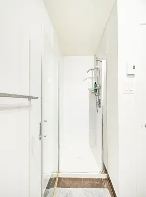 a white bathroom with a shower with a glass door at Charmant appartement au vieux port de Montréal in Montréal