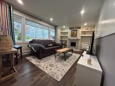 a living room with a couch and a table at Entire floor in a Spacious bungalow ensuite close to beach and train in Pincourt