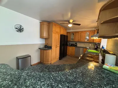 a kitchen with wooden cabinets and a black refrigerator at Entire floor in a Spacious bungalow ensuite close to beach and train in Pincourt