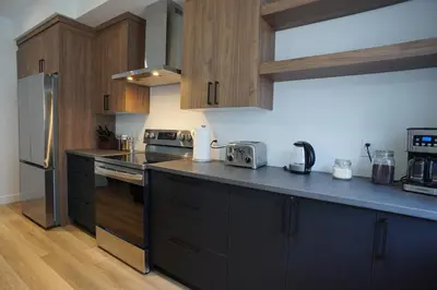 a kitchen with wooden cabinets and a black counter top at Loup in Magog-Orford