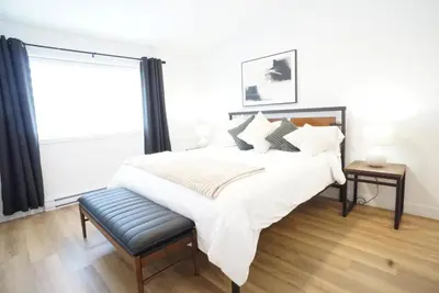a bedroom with a bed with white sheets and a window at Loup in Magog-Orford