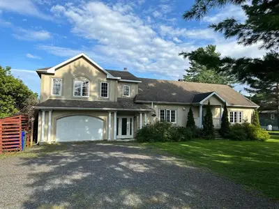 a large white house with a large garage at Havre du lac magog in Sainte-Catherine-de-Hatley
