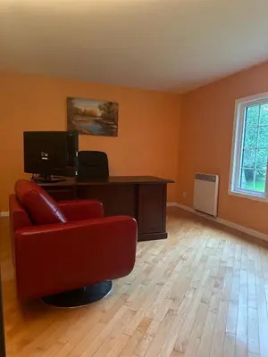 a living room with a red chair and a desk at Havre du lac magog in Sainte-Catherine-de-Hatley
