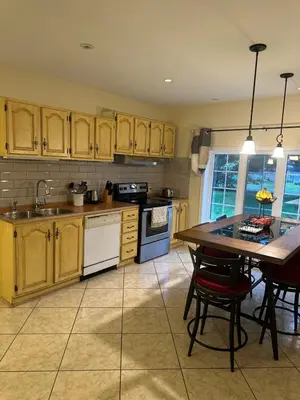 a kitchen with wooden cabinets and a table with chairs at Havre du lac magog in Sainte-Catherine-de-Hatley