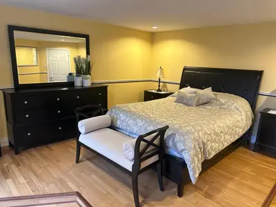a bedroom with a bed and a mirror and a chair at Havre du lac magog in Sainte-Catherine-de-Hatley