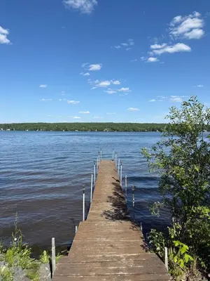 a wooden dock sticking out into a large body of water at Havre du lac magog in Sainte-Catherine-de-Hatley