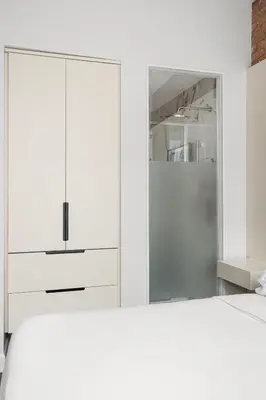 a white bedroom with a bed and a mirror at Nomade Saint Paul in Montréal