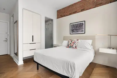 a bedroom with a white bed and a brick wall at Nomade Saint Paul in Montréal
