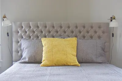 a bed with a yellow pillow and two lamps at Gite La Cache in Beloeil Village