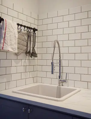 a white kitchen with a sink and utensils at Gite La Cache in Beloeil Village