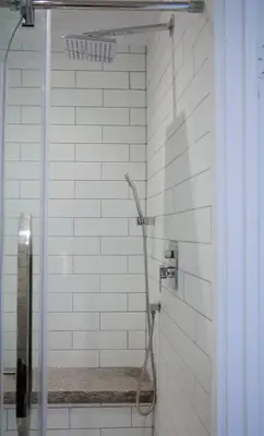 a shower in a bathroom with white tiles at Gite La Cache in Beloeil Village
