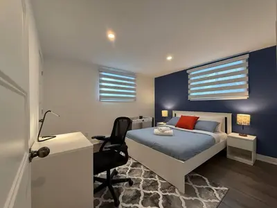 a bedroom with a bed and a desk with a chair at Beautiful Spacious 4BR with Parking, Near Montreal in Longueuil
