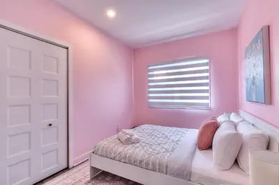 a pink bedroom with a bed and a window at Modern Comforts 3 Bedroom & Full Kitchen & Wifi & Easy Montreal Access in Longueuil