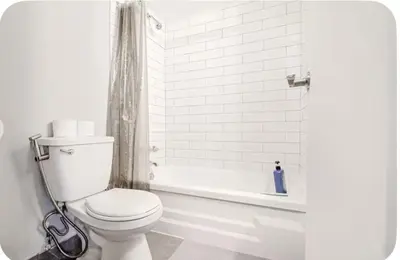 a white bathroom with a toilet and a bath tub at Charmant 1-chambre proche restaurants et attractions in Montréal