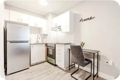 a kitchen with white appliances and a table and a chair at Charmant 1-chambre proche restaurants et attractions in Montréal