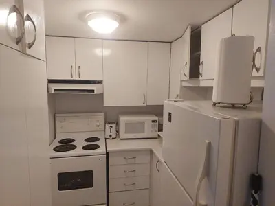 a small kitchen with white cabinets and a white refrigerator at Guy Concordia! Nightlife! Downtown's Essentials! Best City Spot! in Montréal