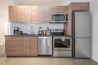 a kitchen with stainless steel appliances and wooden cabinets at Historic Old Montreal Stay - Iconic Location in Montréal