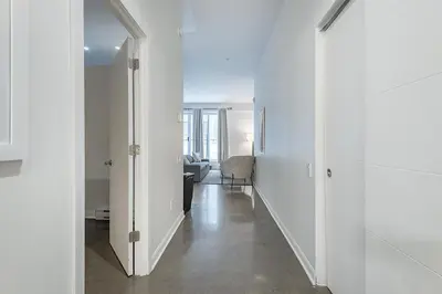 a hallway with white walls and a mirror at Historic Old Montreal Stay - Iconic Location in Montréal