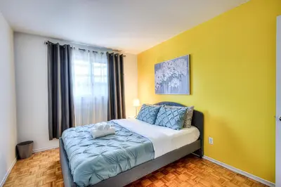 a bedroom with a bed with a yellow wall at Beautiful and Cozy 3BR in Montreal West Island in Montréal