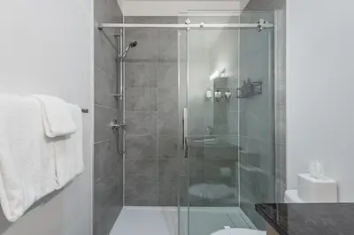 a bathroom with a shower with a glass door at Chic Old Montreal Retreat - Iconic Location in Montréal