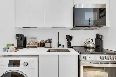a white kitchen with a stove and a microwave at The Speakeasy Suite 503 With Parking in Montréal