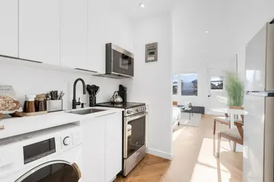 a white kitchen with a sink and a stove at The Speakeasy Suite 503 With Parking in Montréal