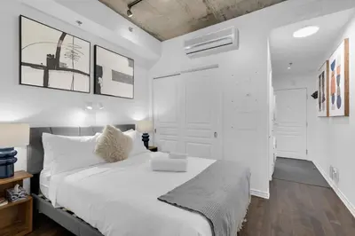 a white bedroom with a large white bed and white walls at Flat at the Foot of the Mountain With Parking in Montréal