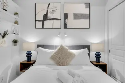a bedroom with a white bed with two lamps at Flat at the Foot of the Mountain With Parking in Montréal