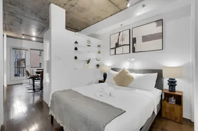 a white bedroom with a large bed and a desk at Flat at the Foot of the Mountain With Parking in Montréal