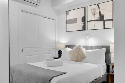 a white bedroom with a large bed with white pillows at Flat at the Foot of the Mountain With Parking in Montréal