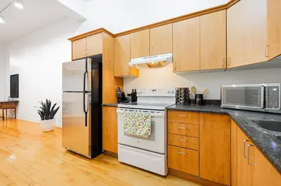a kitchen with wooden cabinets and stainless steel appliances at Loft Spacieux Down Town in Montréal
