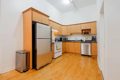 a kitchen with wooden cabinets and a stainless steel refrigerator at Loft Spacieux Down Town in Montréal