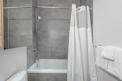a bathroom with a shower with a white shower curtain at Luxury Old Montreal Suite with Soaring Ceilings in Montréal