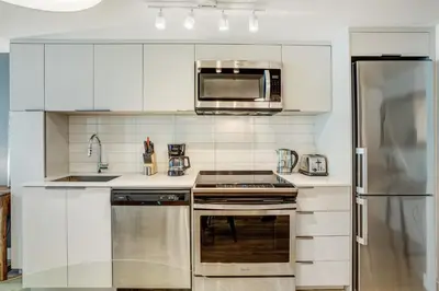 a kitchen with white cabinets and a stainless steel appliances at Pet-Friendly Furnished 1B Rental in Montreal with Skyline Views & Concierge in Montréal