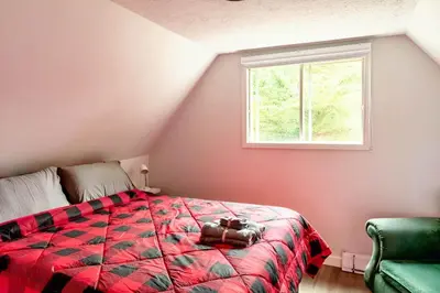 a bedroom with a bed with a red blanket and a window at Waterfront with Spa - Le Retro in Windsor