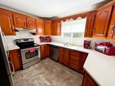 a kitchen with wooden cabinets and a stove top oven at Waterfront with Spa - Le Retro in Windsor