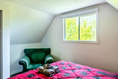 a bedroom with a bed and a green chair at Waterfront with Spa - Le Retro in Windsor