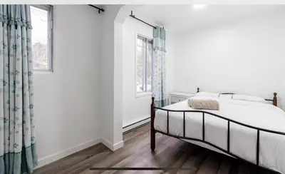 a white bedroom with a bed and a window at Comfortable 4B Unit-Close to City Attractions in Montréal
