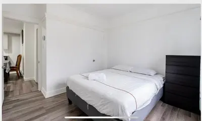 a white bedroom with a bed and a desk at Comfortable 4B Unit-Close to City Attractions in Montréal