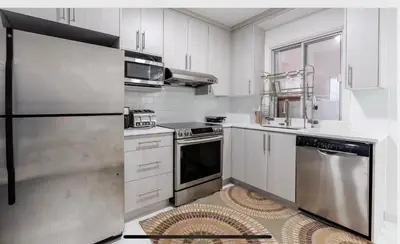 a kitchen with white cabinets and stainless steel appliances at Comfortable 4B Unit-Close to City Attractions in Montréal